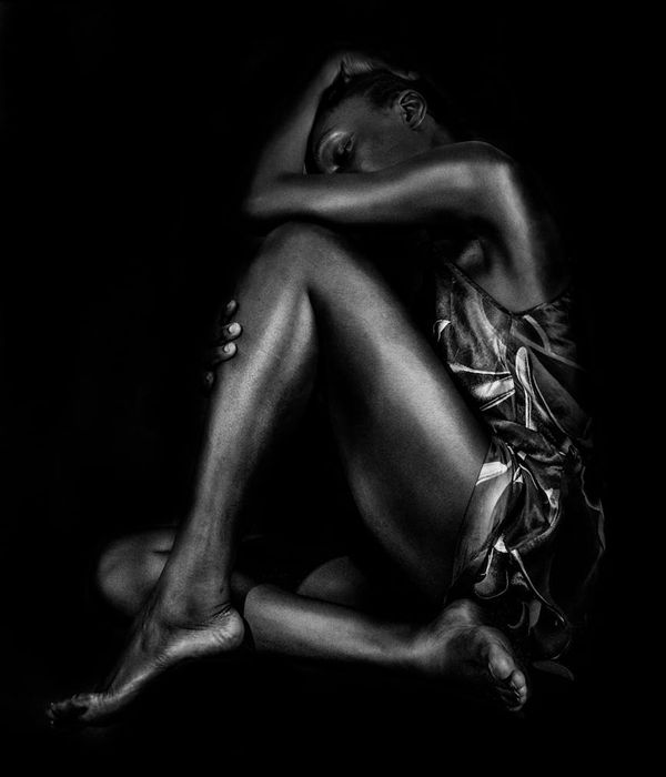 Woman performing a powerful static hold pose in a minimalist dark room.